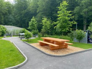 Zone aménagée avec un jardin et une table en bois dans un environnement vert Giziaux Epalinges en Suisse